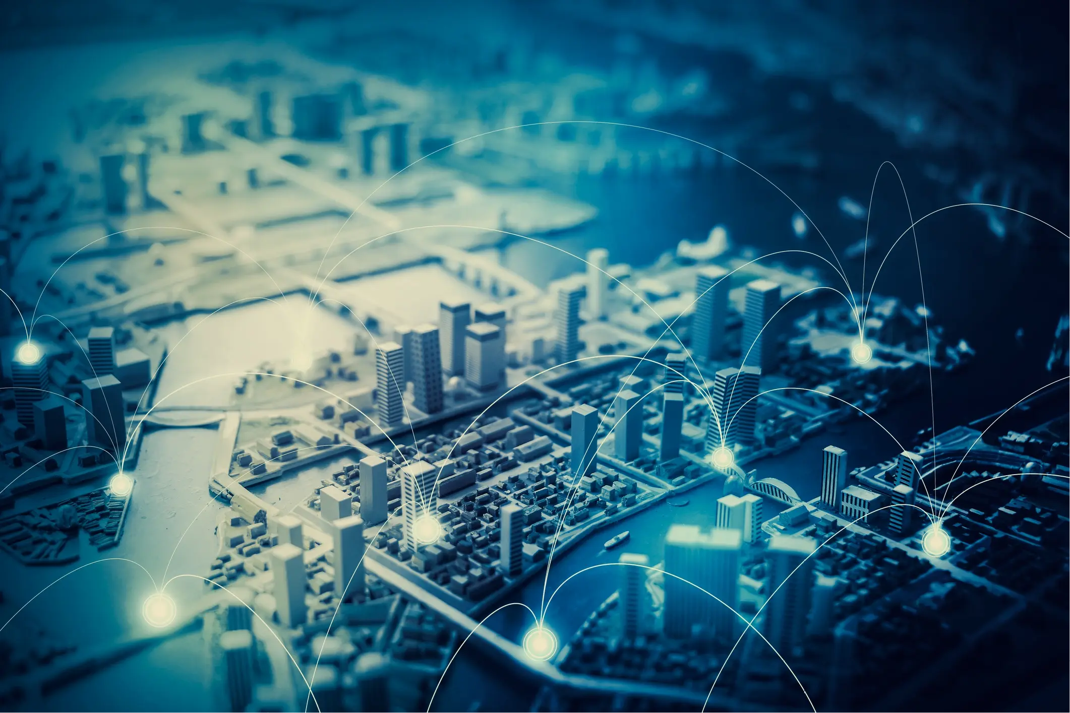 Aerial view of a city model with glowing connection points linked by curved lines, representing enterprise-scale technology connectivity across multiple locations.