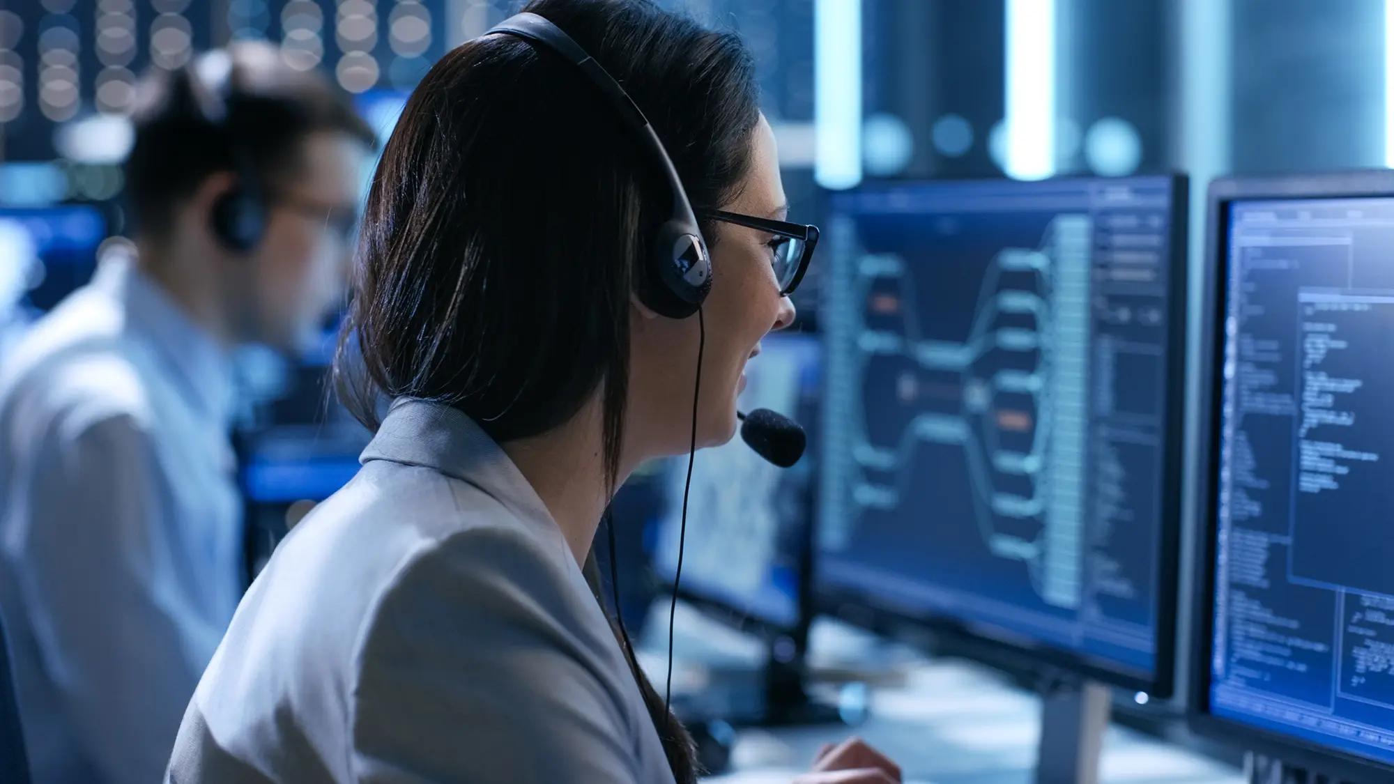 IT dispatch coordinator wearing a headset and managing network monitoring dashboards across multiple screens.
